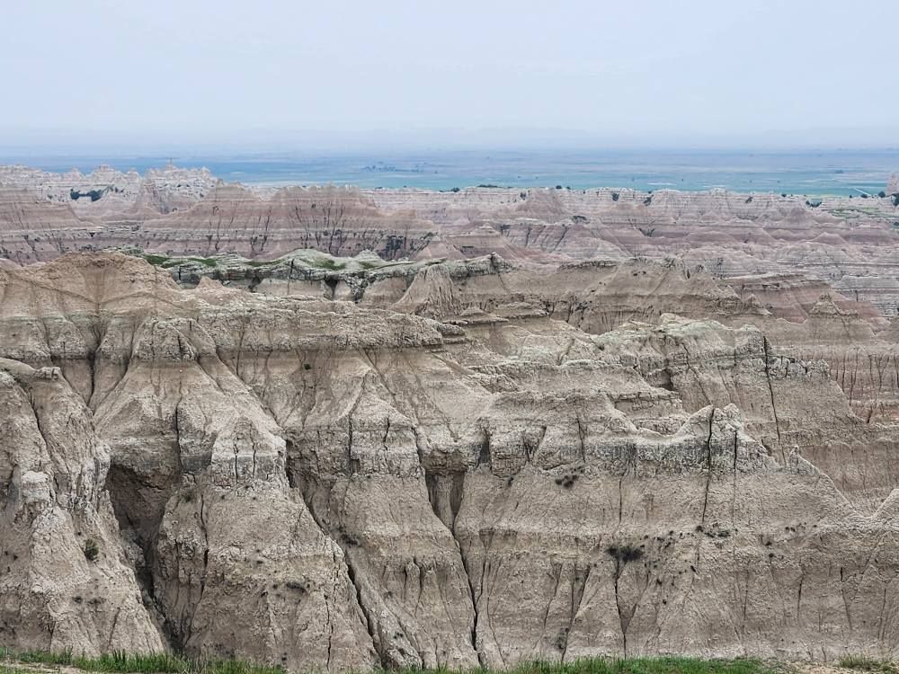 Badlands National Park landscape with layered rock formations under a hazy sky.