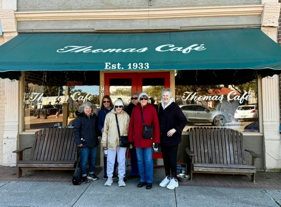 Group of people in front of Thomas Cafe with green awning, red door. Cafe established in 1933.