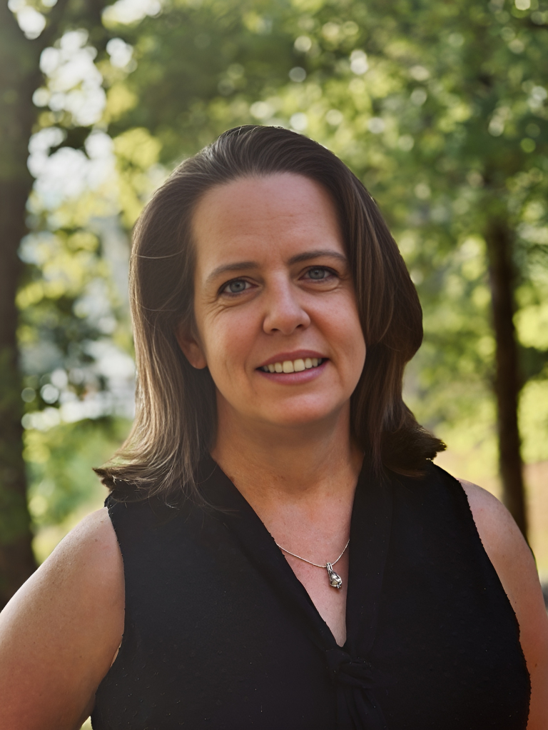 A woman in a black shirt and necklace is smiling for the camera.
