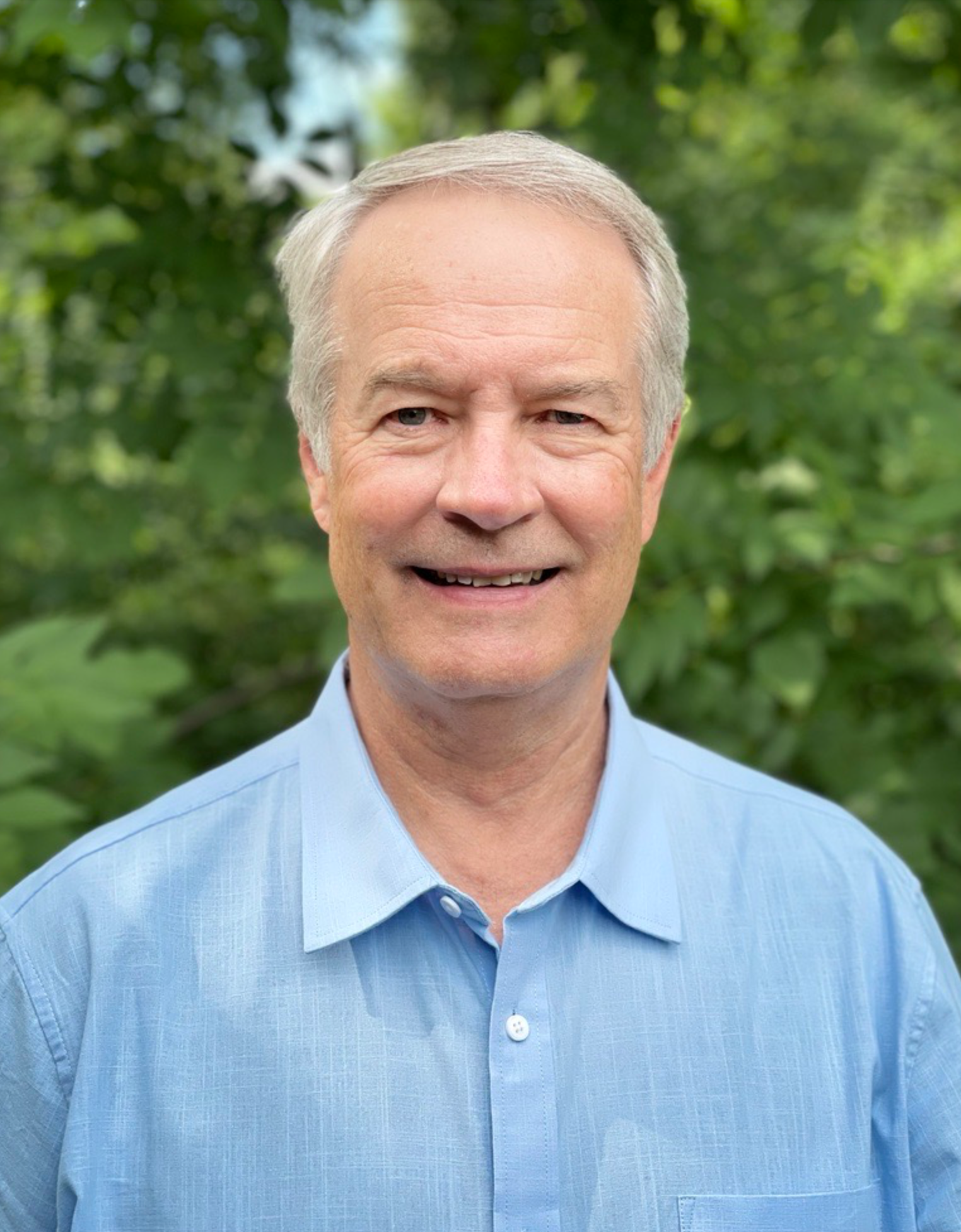 A man in a blue shirt is smiling for the camera.