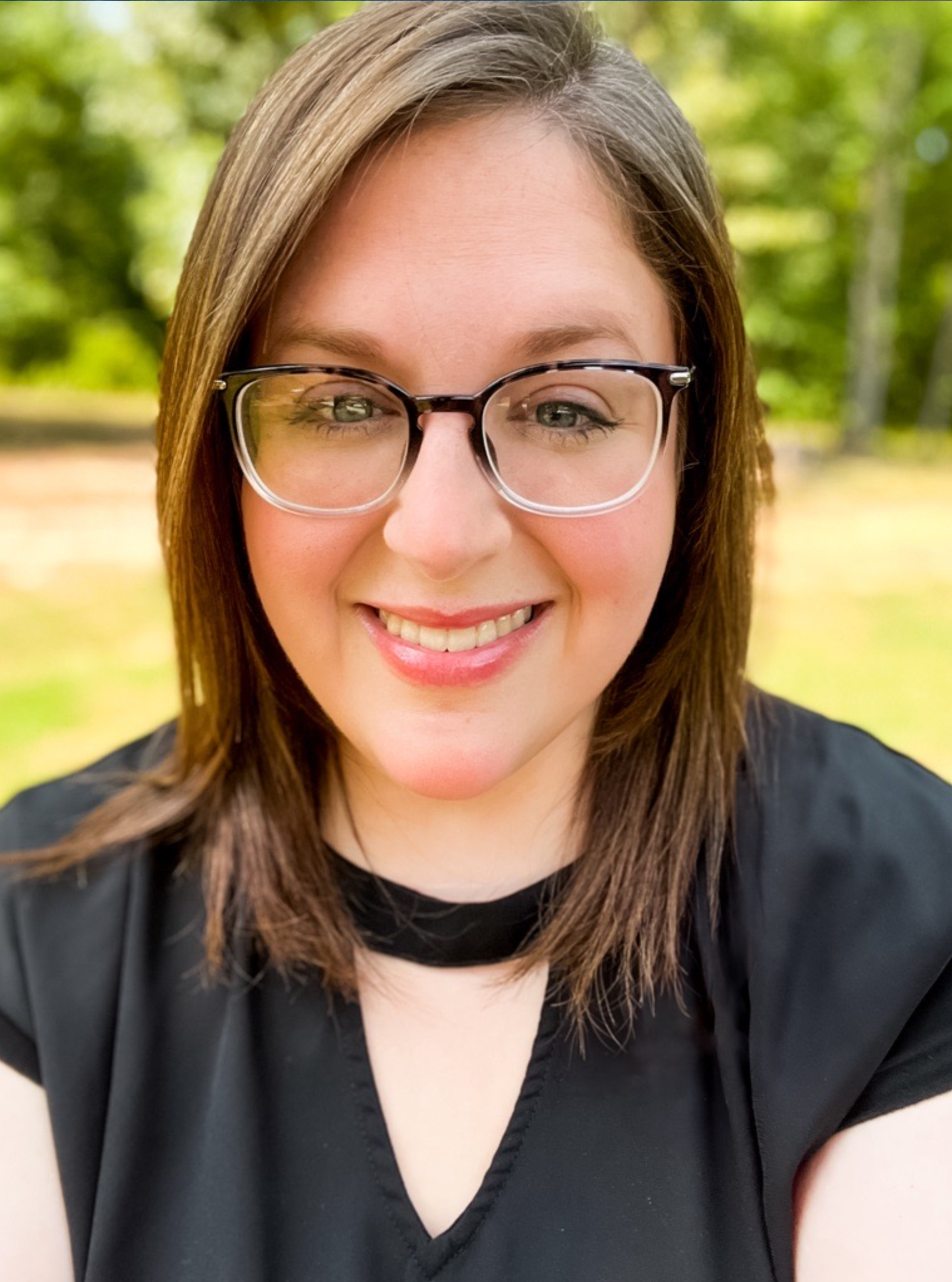 A woman wearing glasses and a black shirt is smiling for the camera.