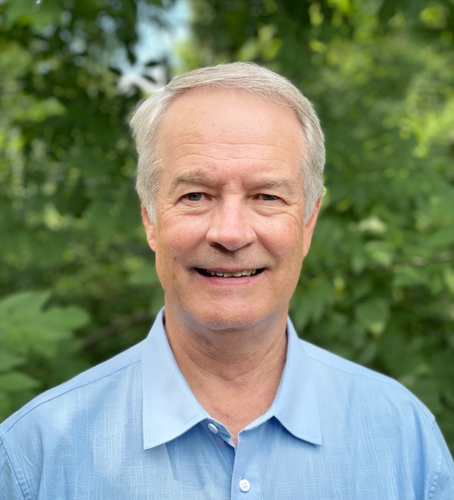 A man in a blue shirt is smiling for the camera.