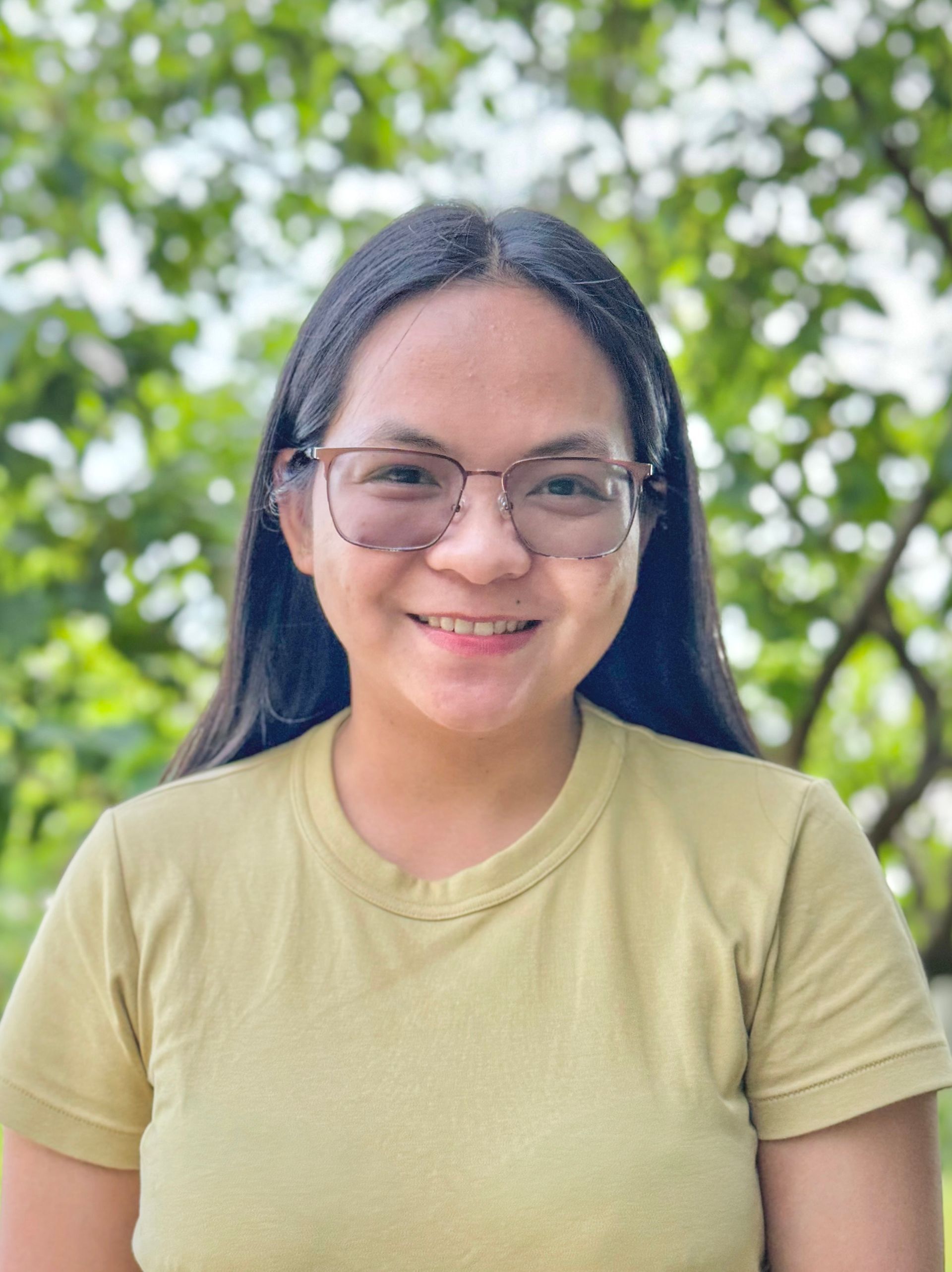 A woman wearing glasses and a yellow shirt is smiling for the camera.