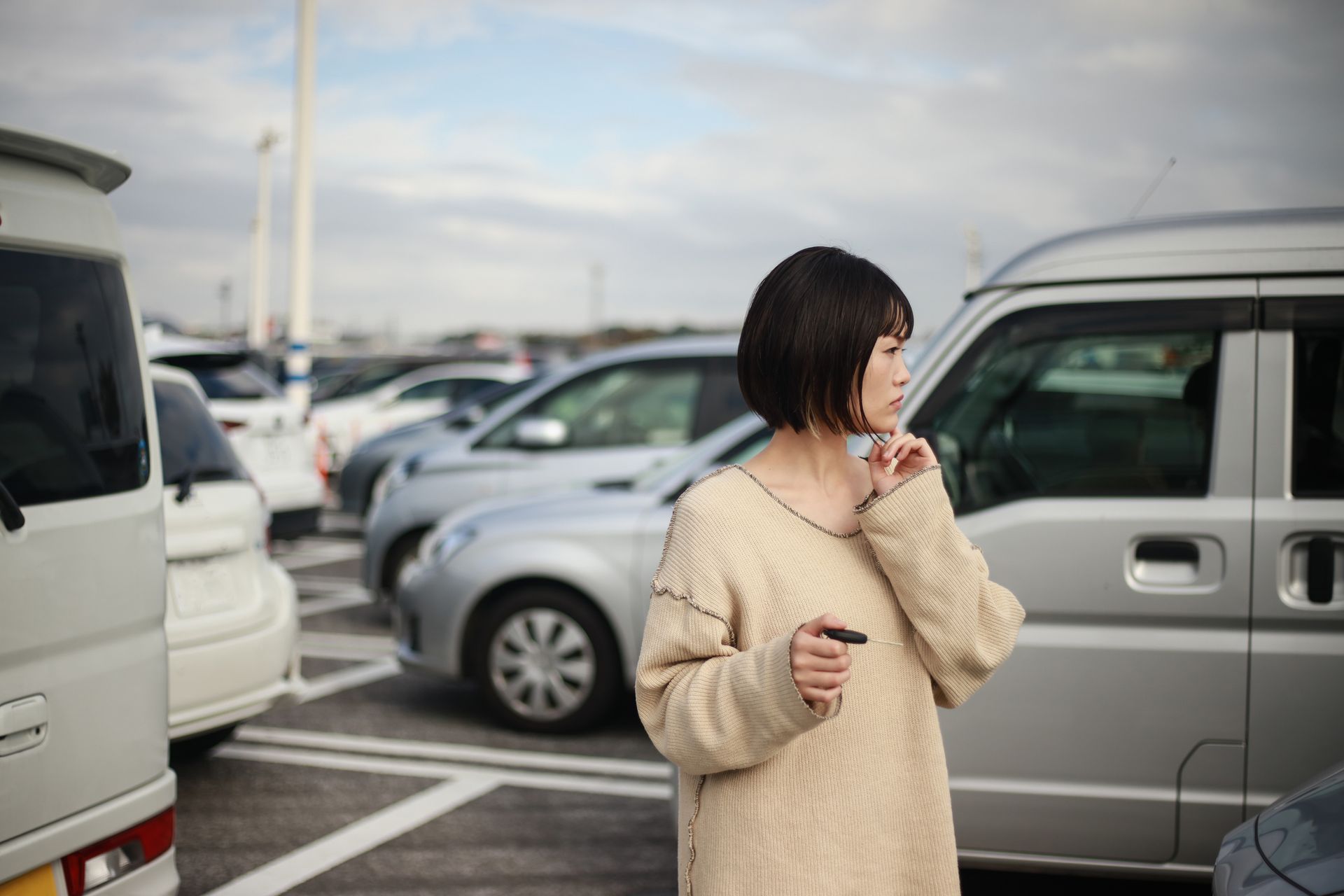 A woman is standing in a parking lot next to a van.
