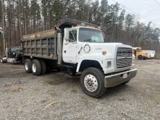 White dump truck parked outdoors on gravel.
