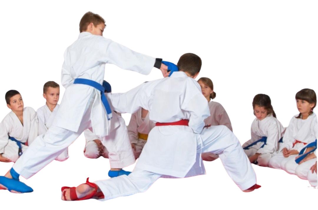 A group of kids in karate uniforms are sitting on the floor drinking water