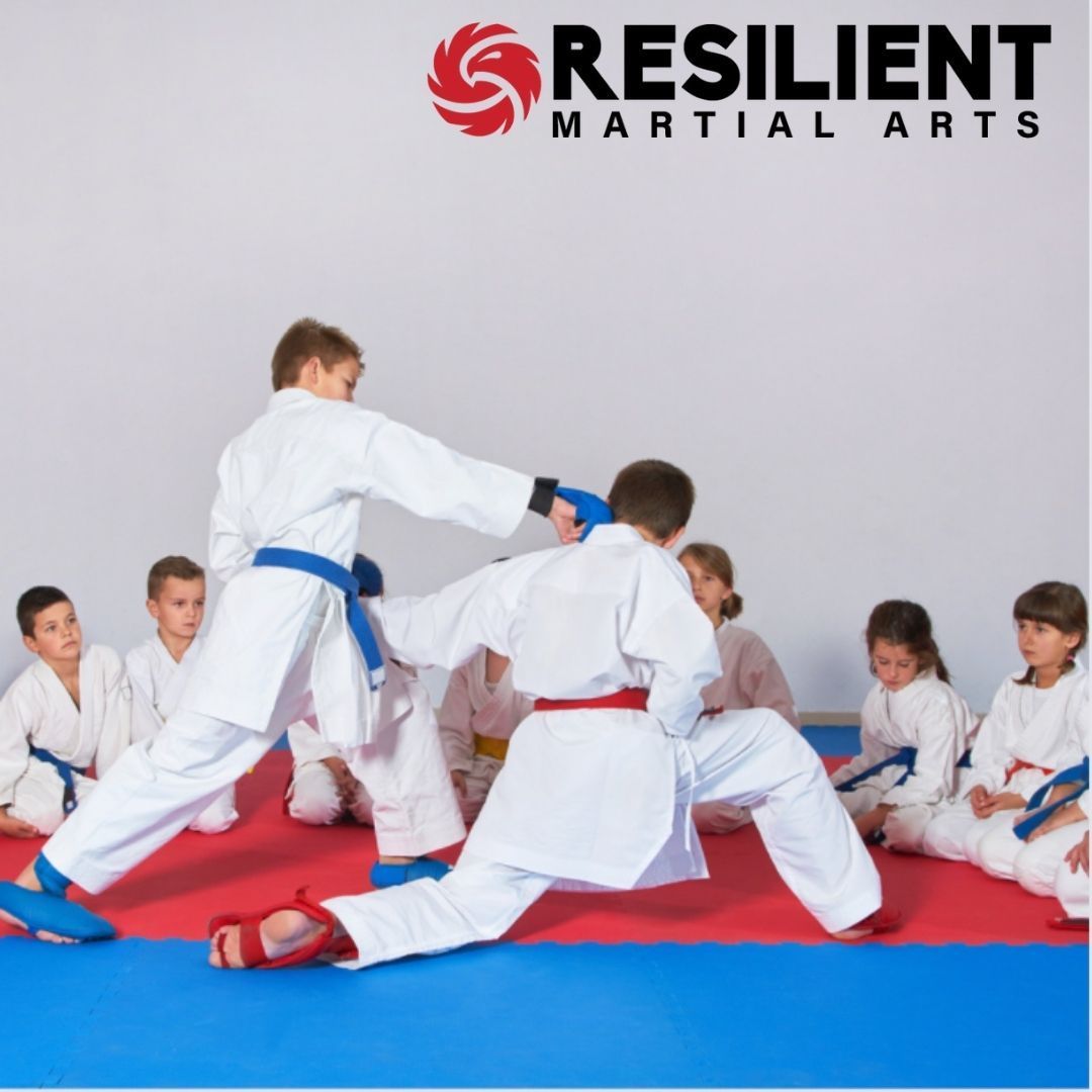 A group of young children in karate uniforms are posing for a picture.