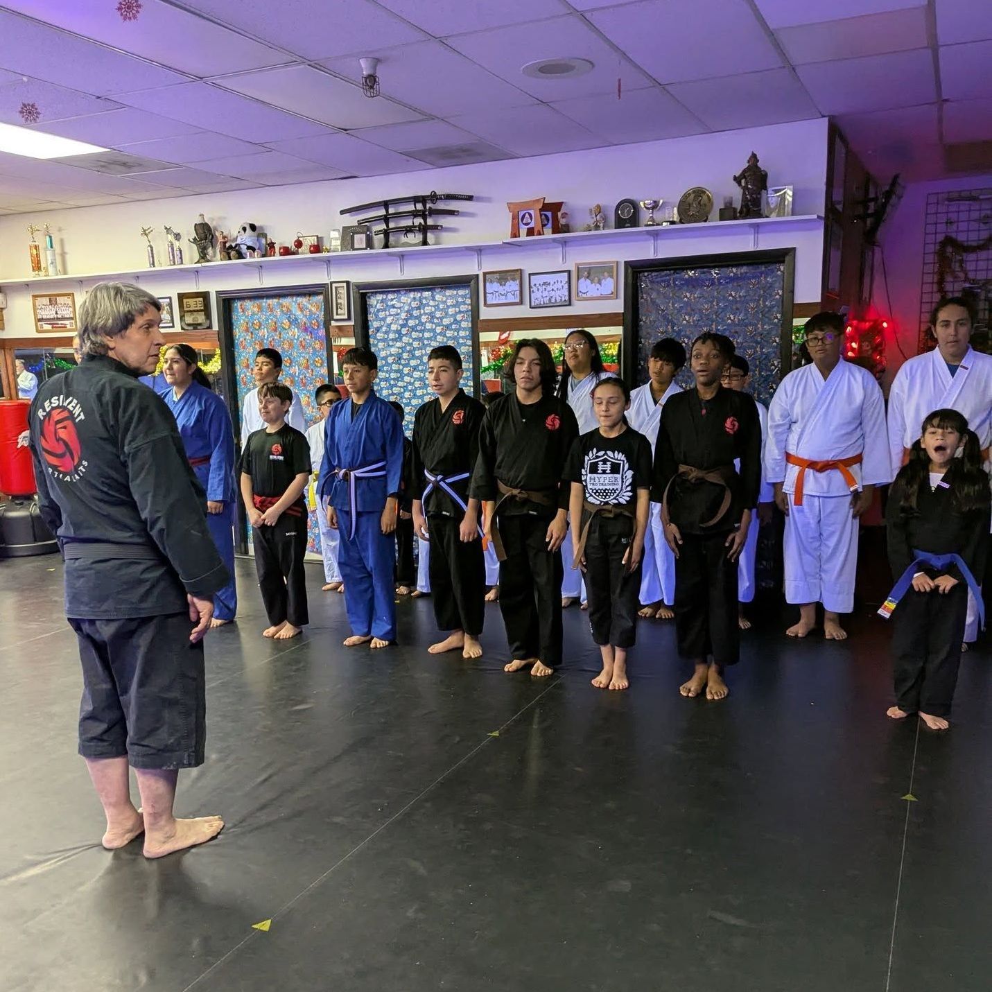 A young girl in a karate uniform is sitting on the floor.