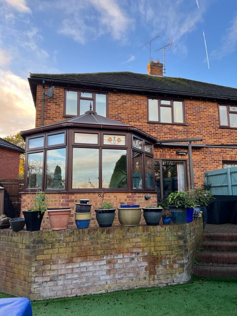 a brick house with a conservatory and potted plants in front of it .