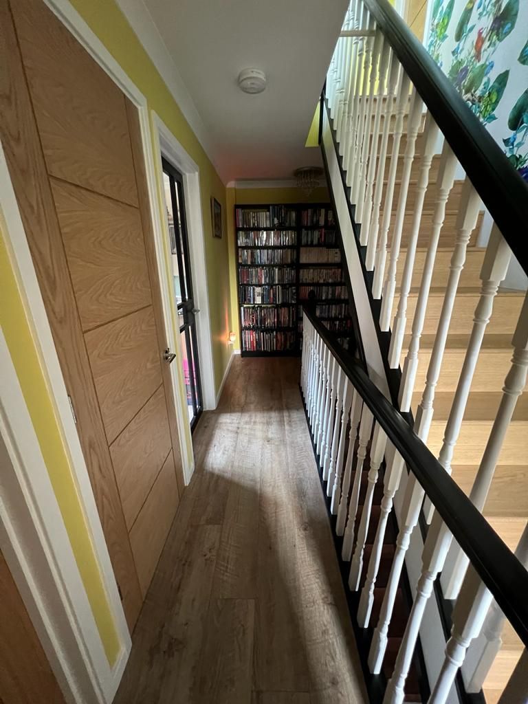 a hallway with stairs and a bookshelf in the background .