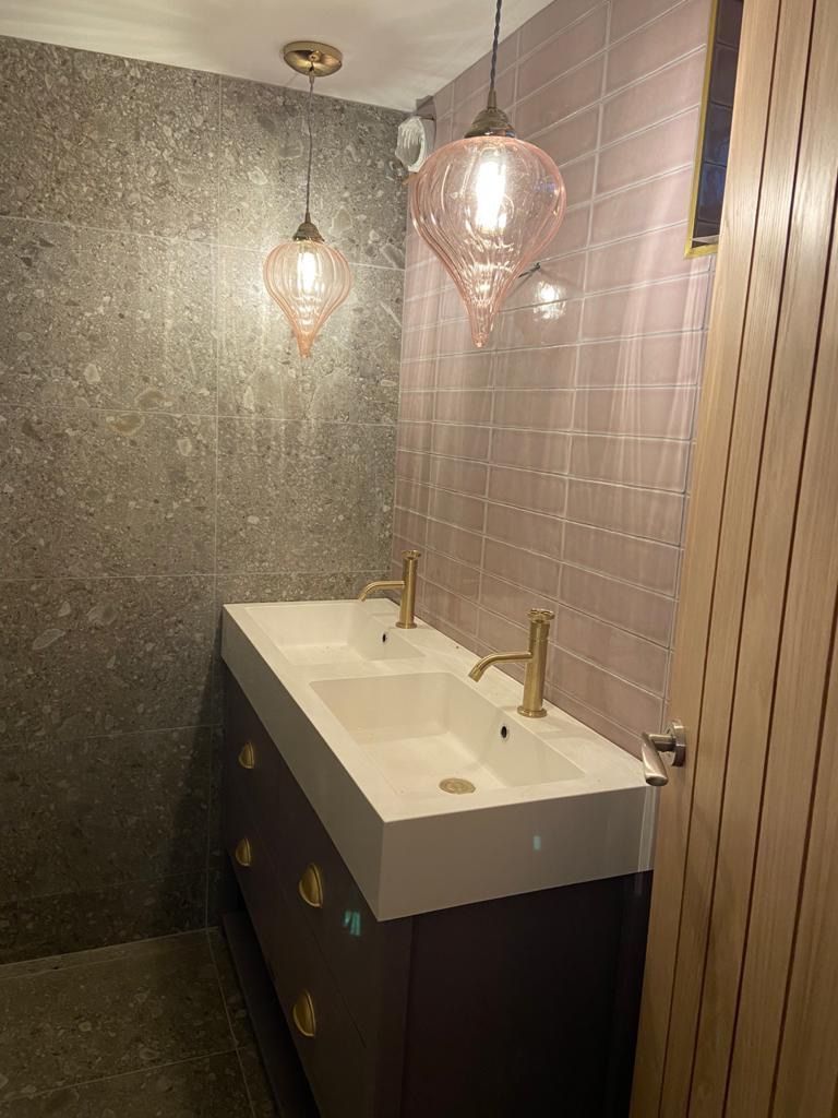 a bathroom with two sinks and two lamps hanging from the ceiling .
