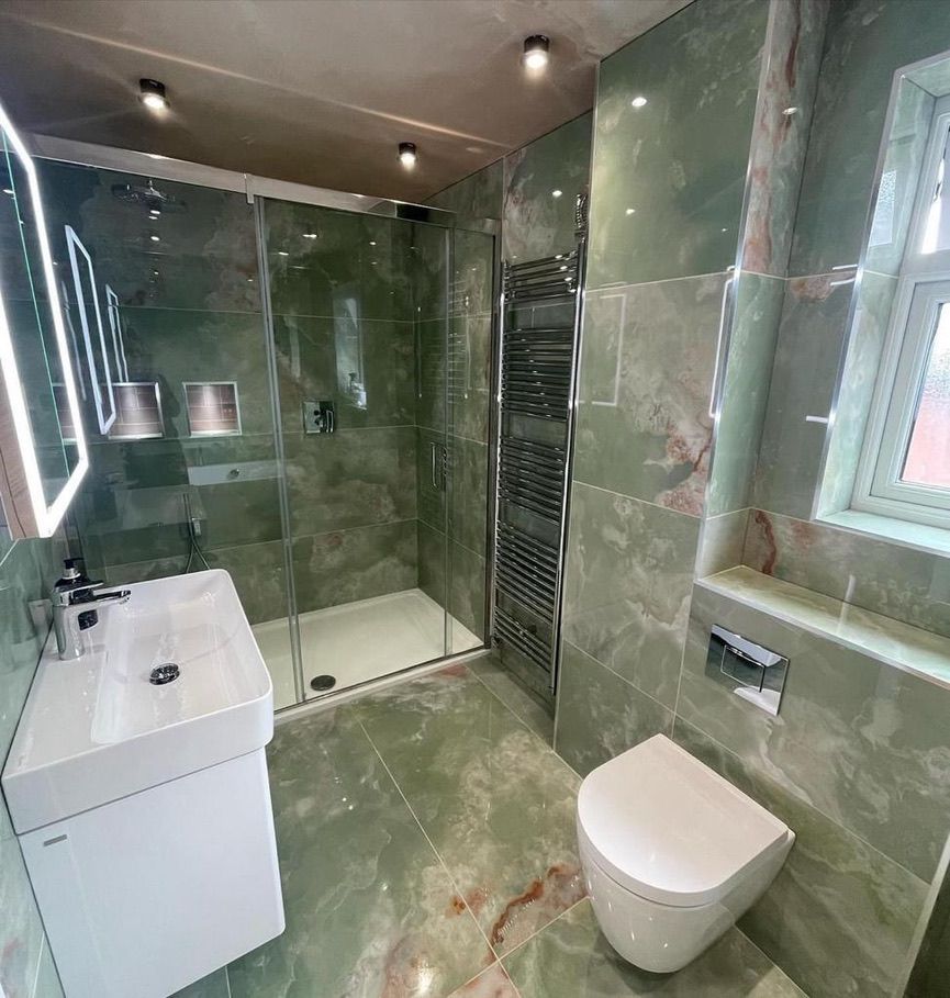 a bathroom with a toilet , sink , shower and mirror .