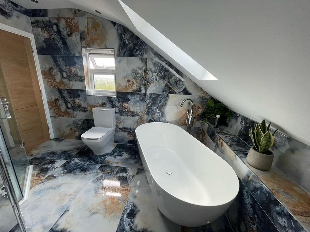 a bathroom with a bathtub , toilet and shower .