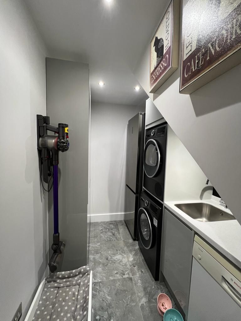 a laundry room with a washer and dryer , a vacuum cleaner , and a sink .