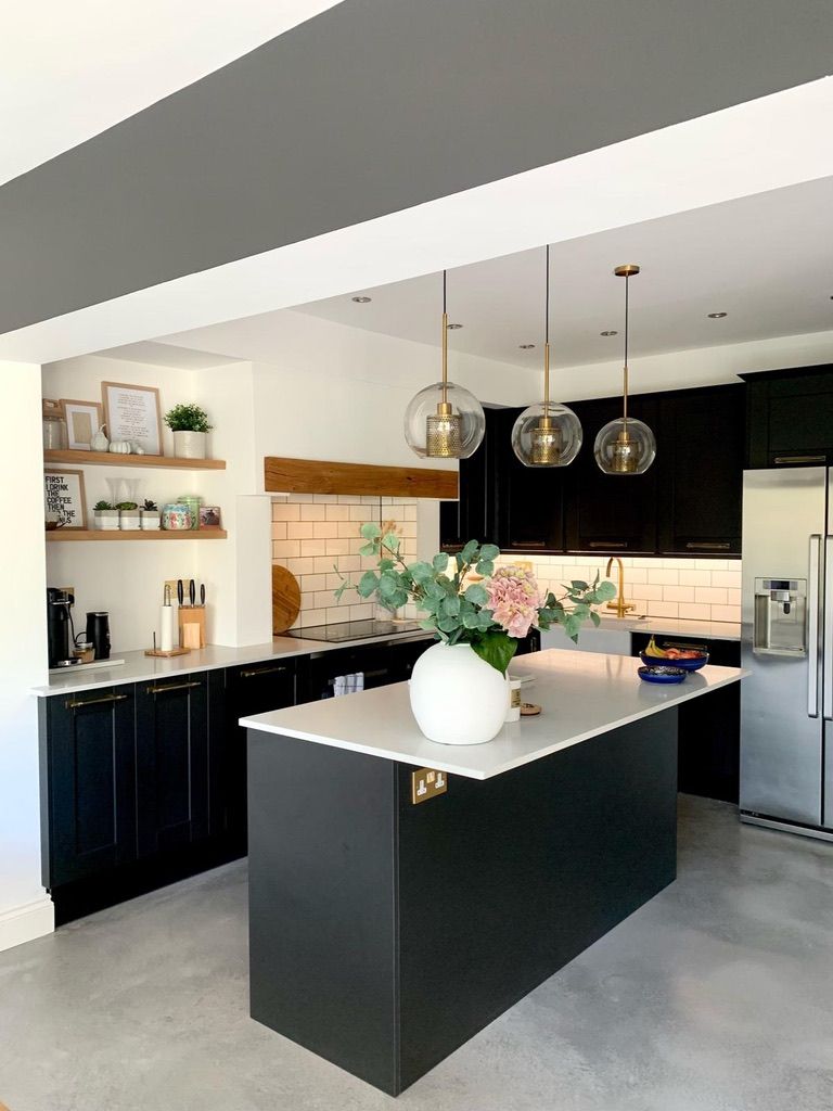 a kitchen with black cabinets and a large island in the middle .