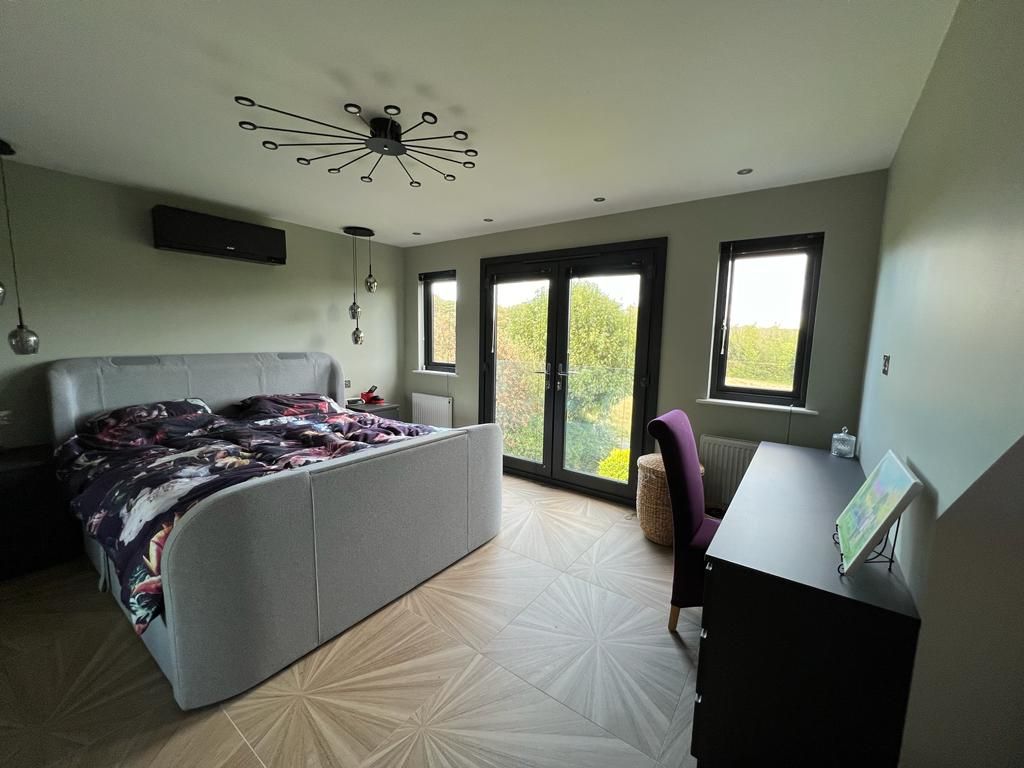 a bedroom with a large bed , desk , chair and sliding glass doors .