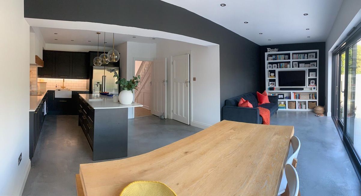 a renovated kitchen, diner and living room with a wooden table and chairs and a couch .