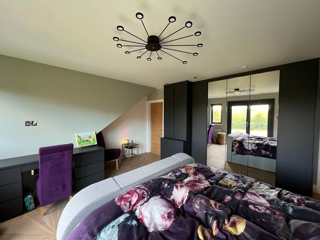 a bedroom with a large bed , a desk , a chair and a clock on the ceiling .