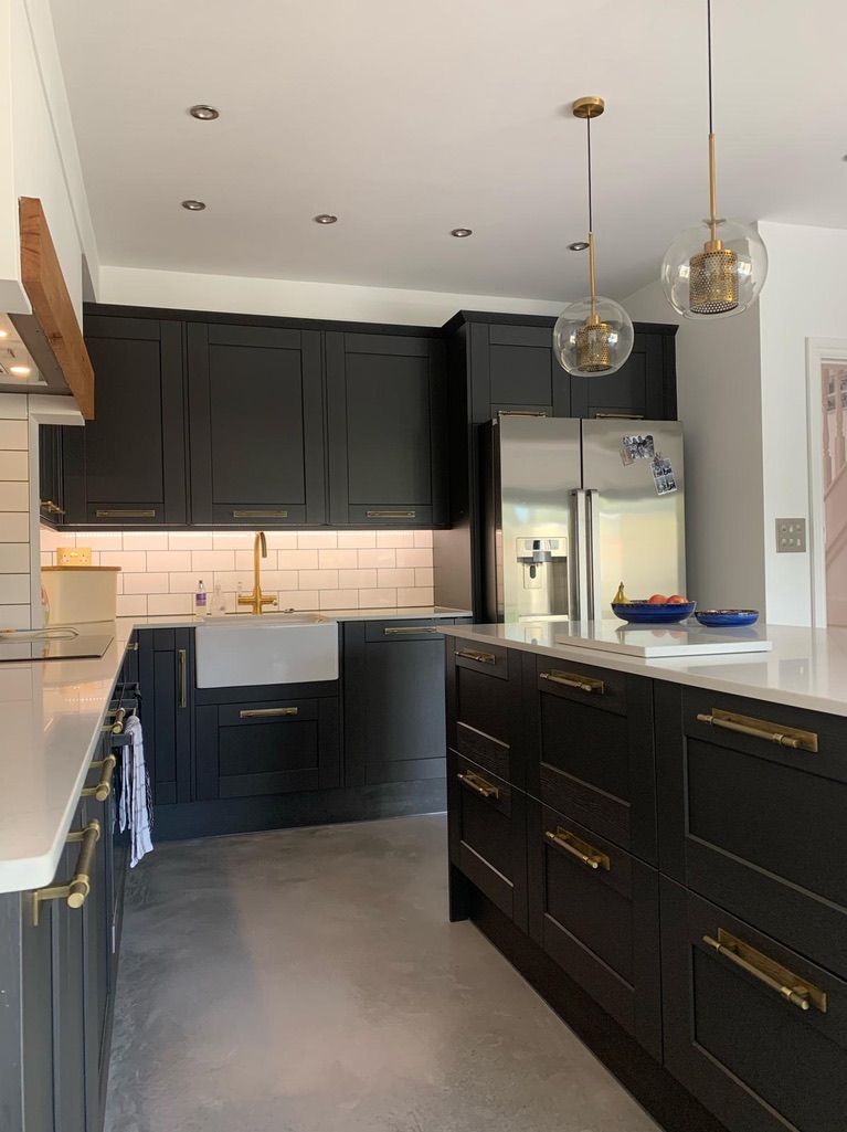a kitchen with black cabinets and gold handles