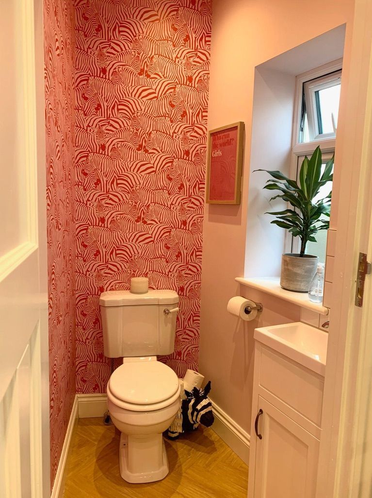 a bathroom with a toilet , sink , and pink wallpaper .