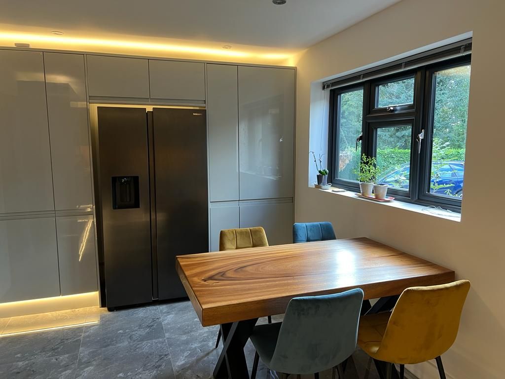 a kitchen with a wooden table and chairs and a refrigerator .