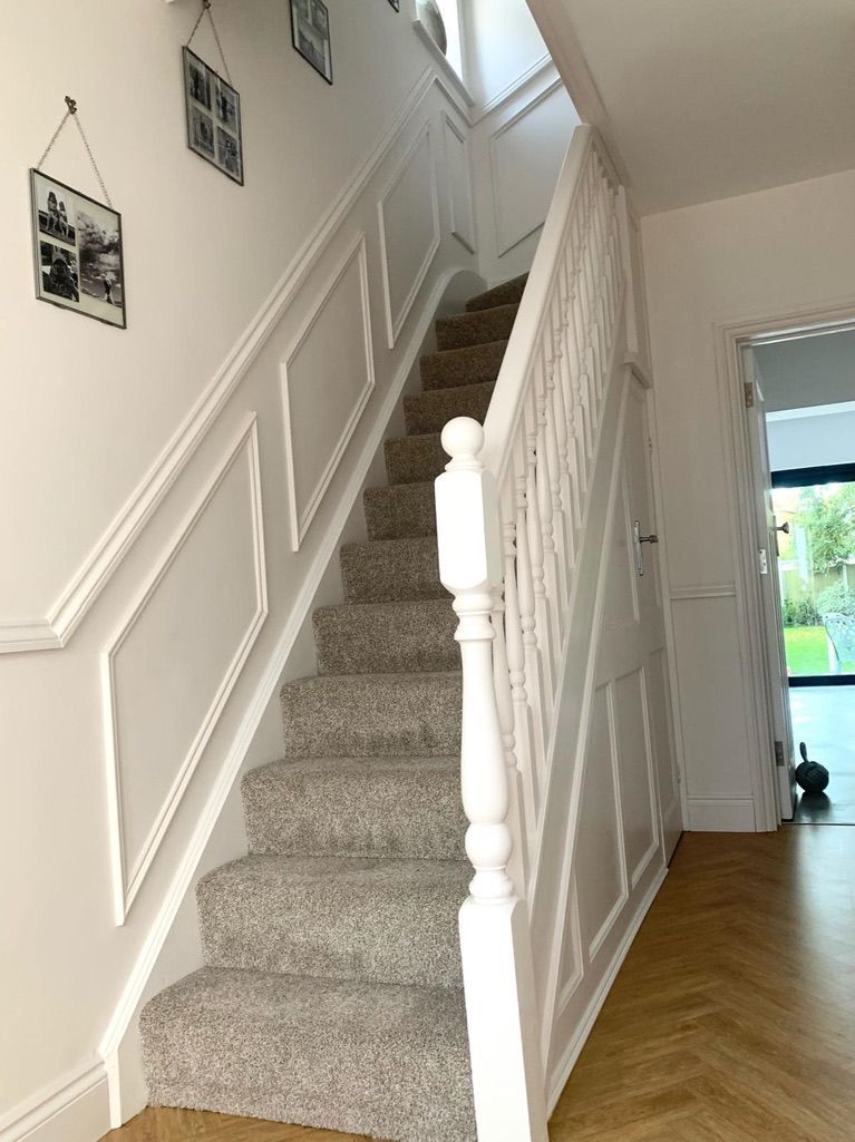 a staircase with carpeted steps and a white railing in a hallway .