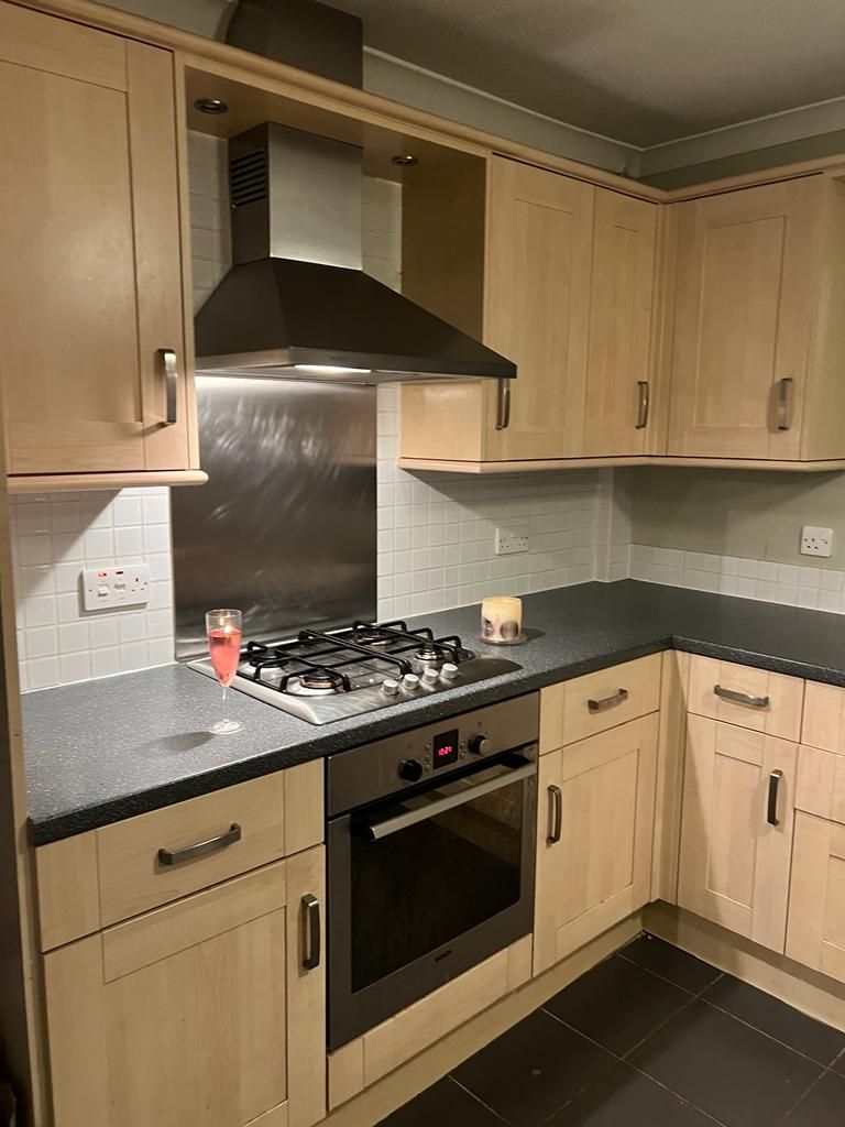 old kitchen with wooden cabinets , a stove top oven , and a hood .