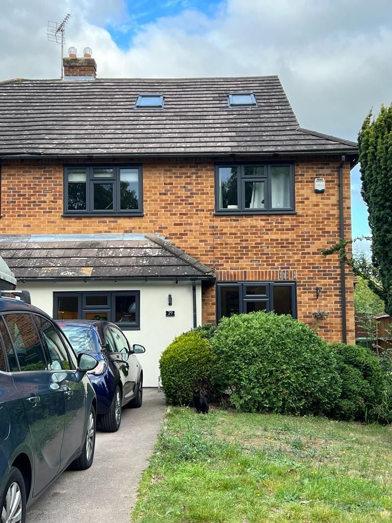a brick house in Essex with two cars parked in front of it .