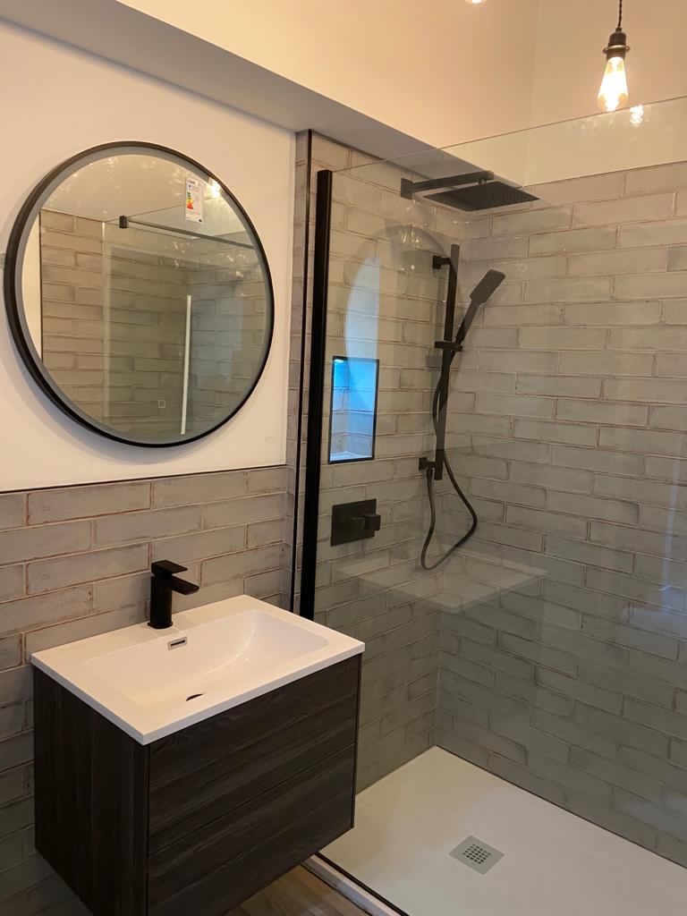 a modern bathroom with one sink, a round mirror and a shower