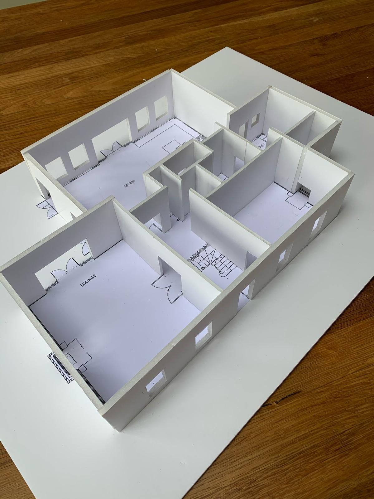 a model of a house is sitting on a wooden table .