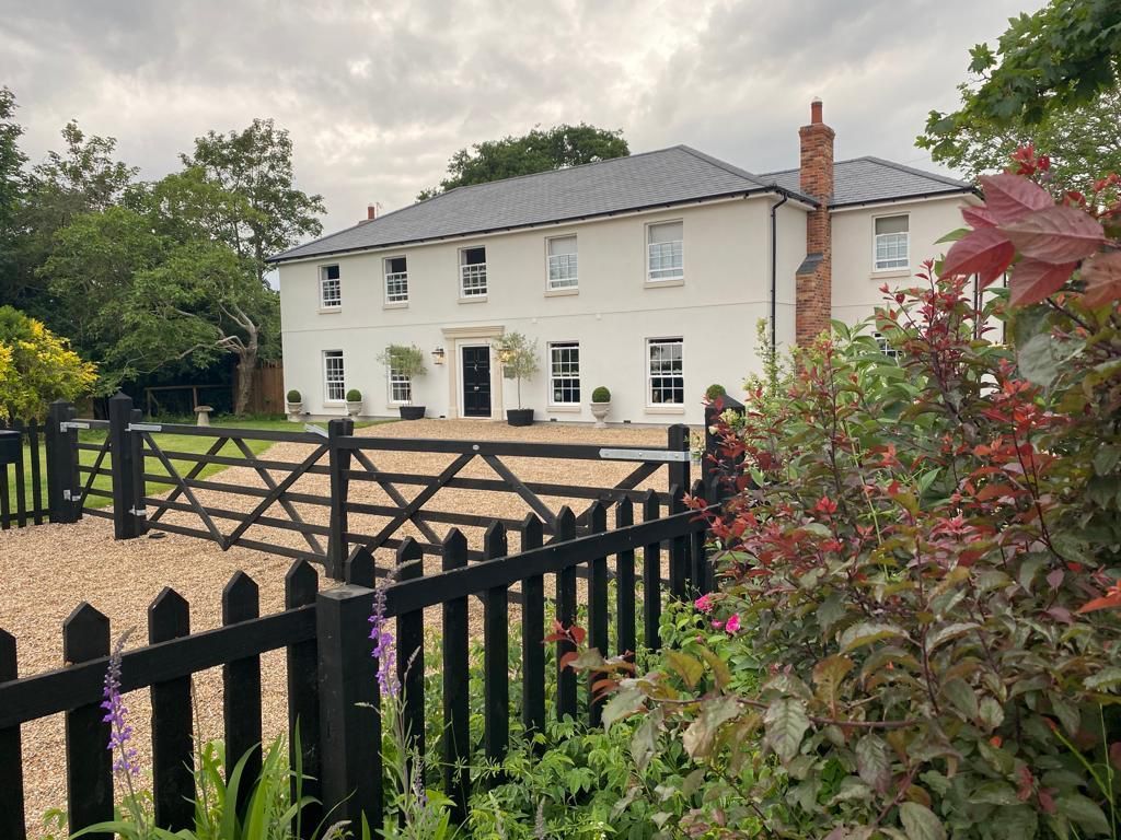 a new build in fambridge essex large white house with a black fence in front of it