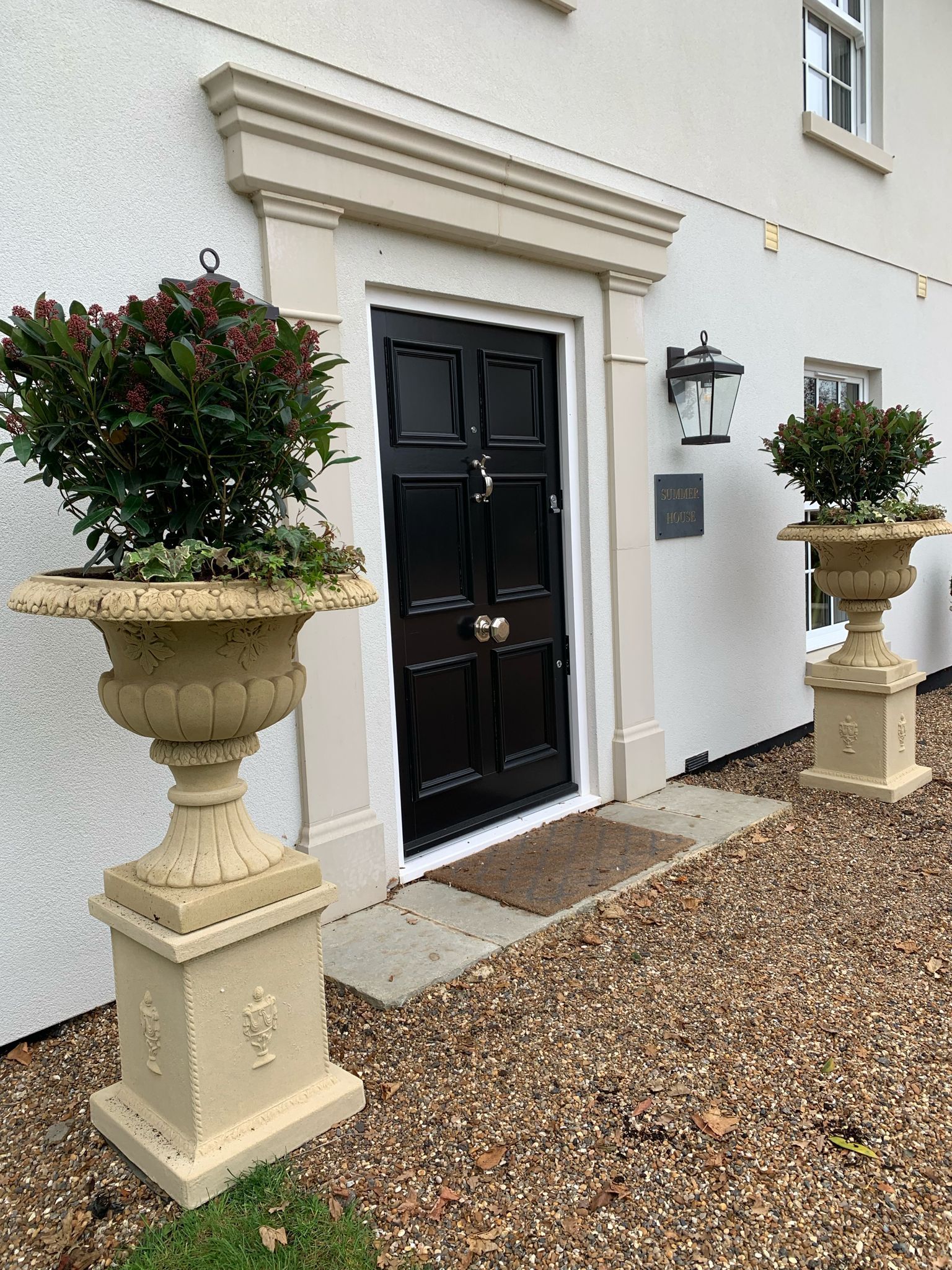 a house with a black door and two planters in front of it .