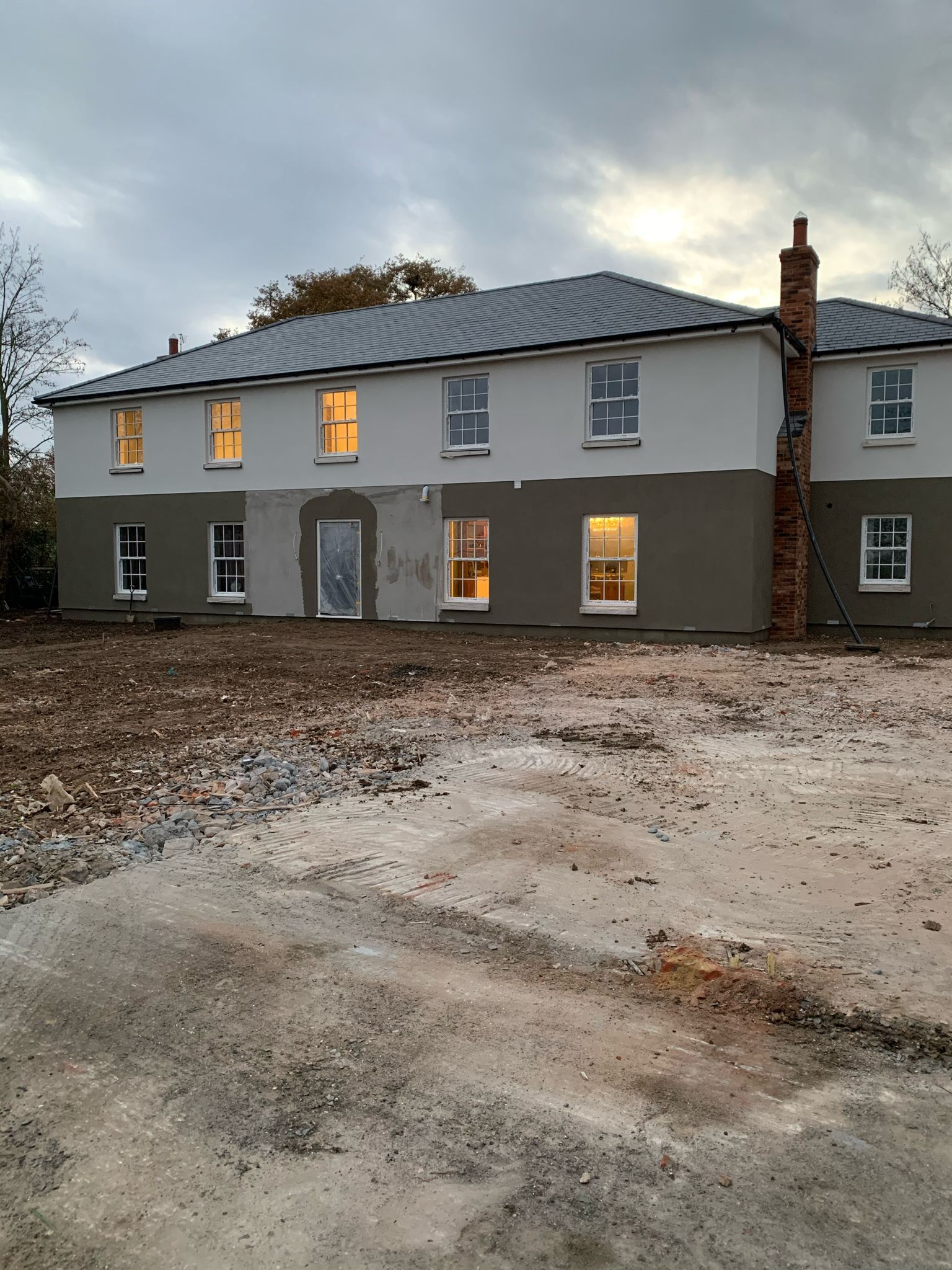 a large house with a lot of windows is sitting on top of a dirt field .