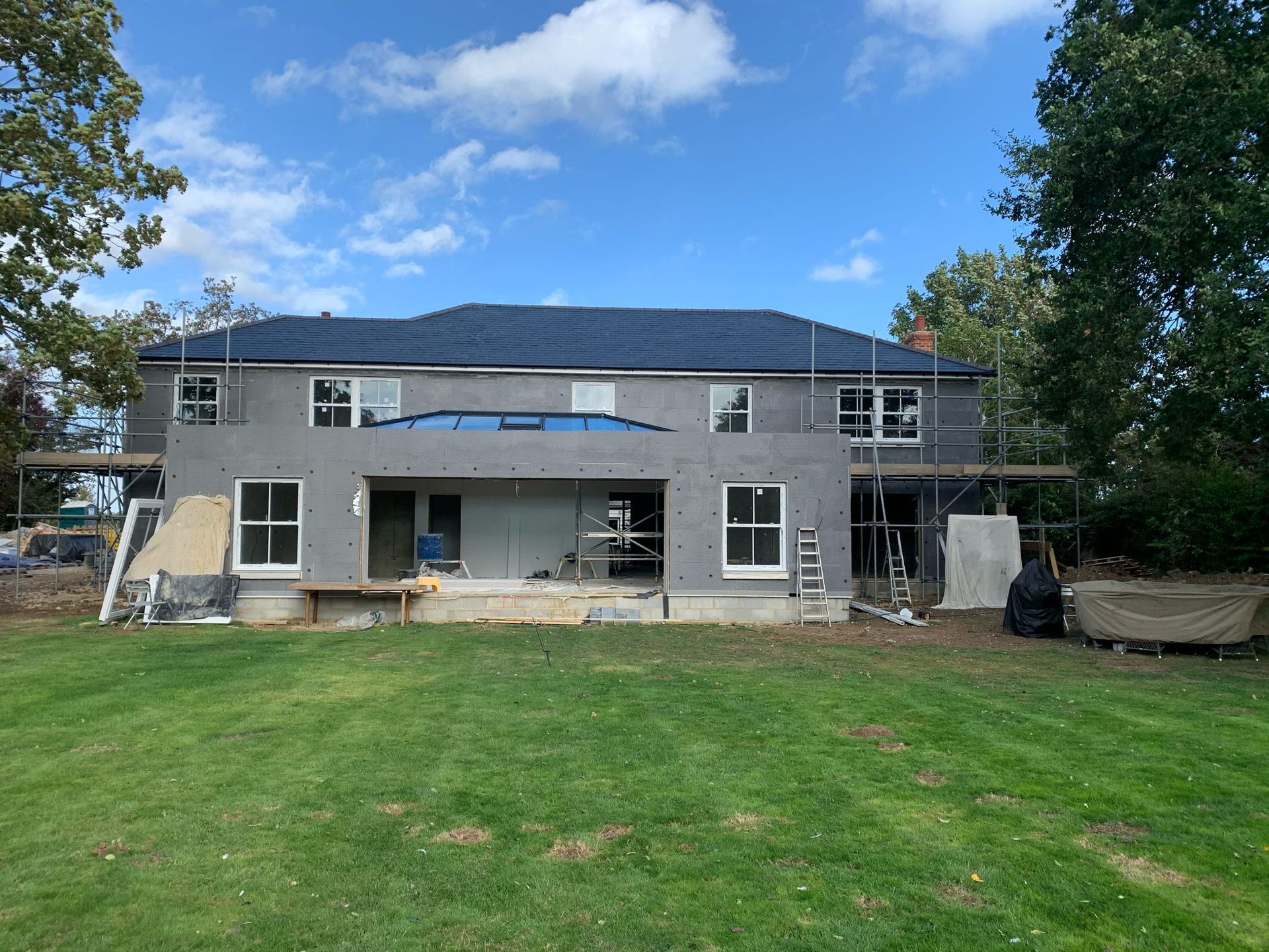 a large house is being built in the middle of a lush green field .
