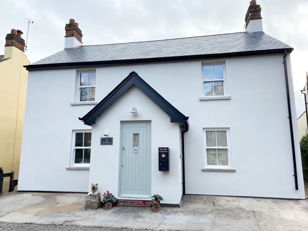 a white house with a blue door and a black roof