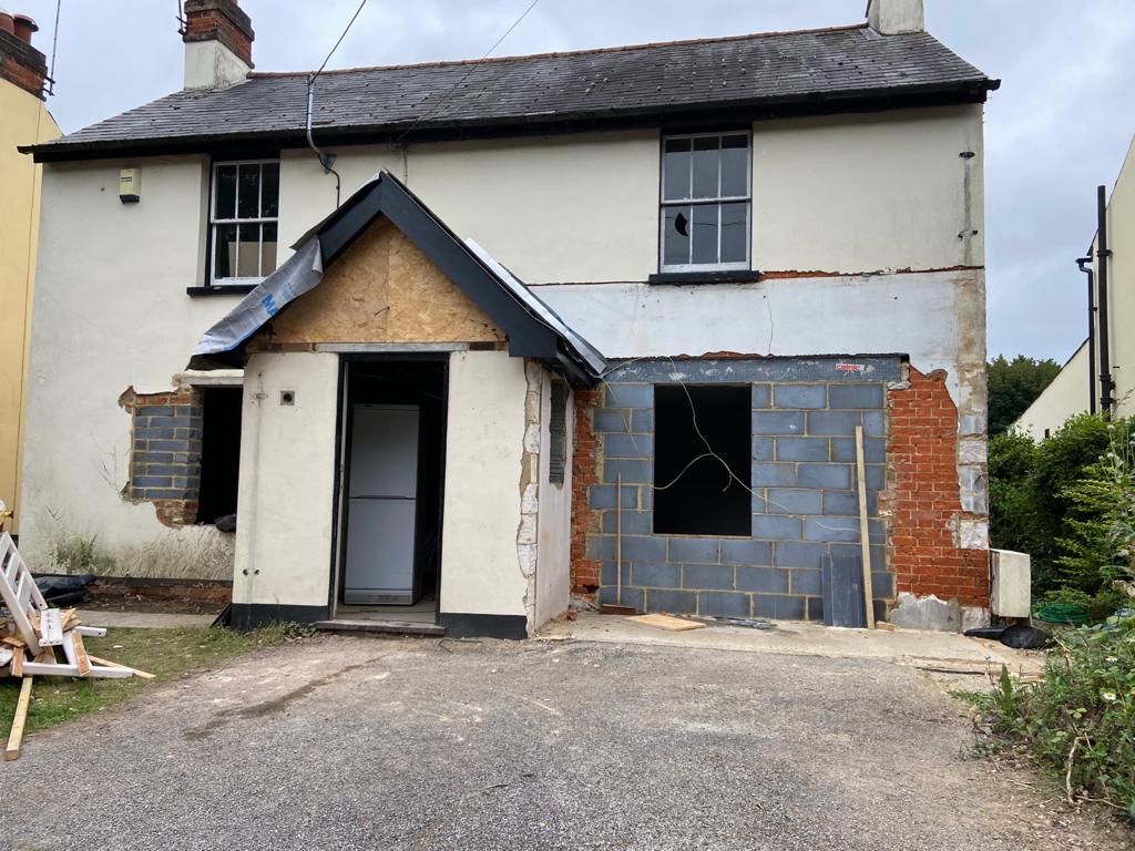 a white house with a black roof is being remodelled