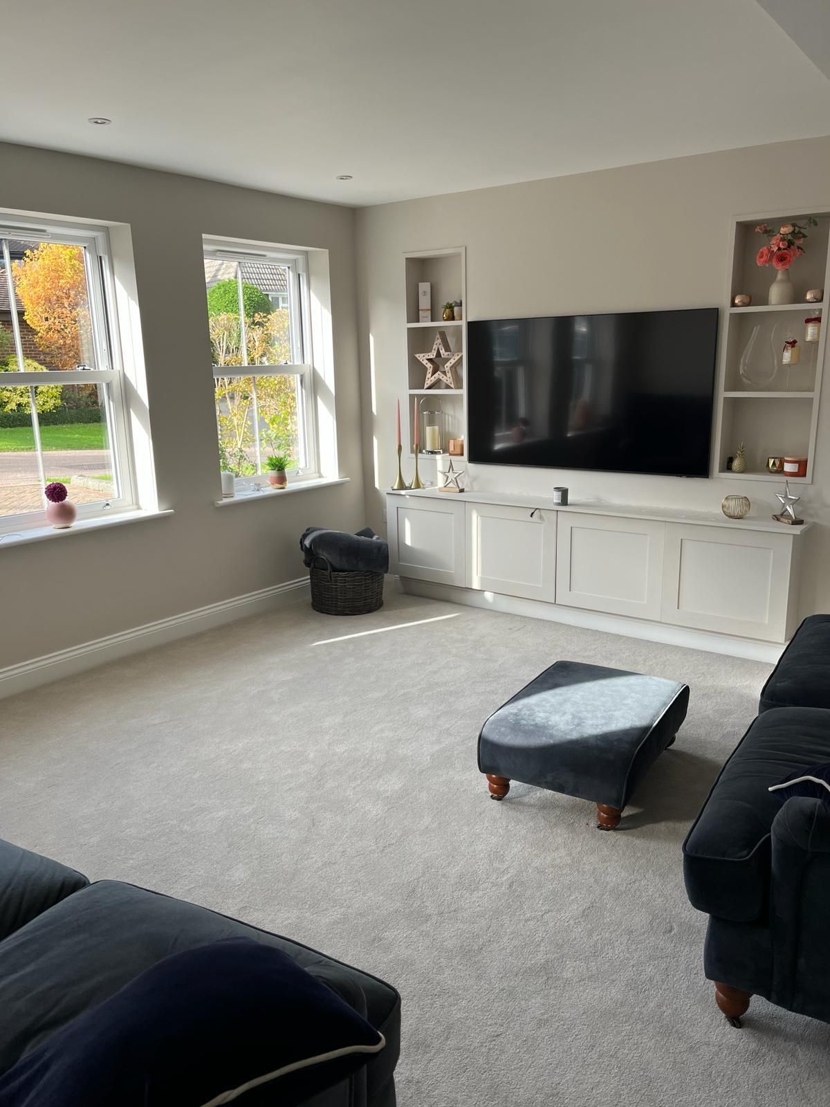 a living room with a couch , ottoman , and television .