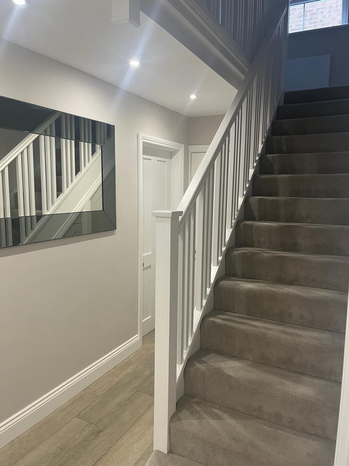 a hallway with stairs and a mirror on the wall .