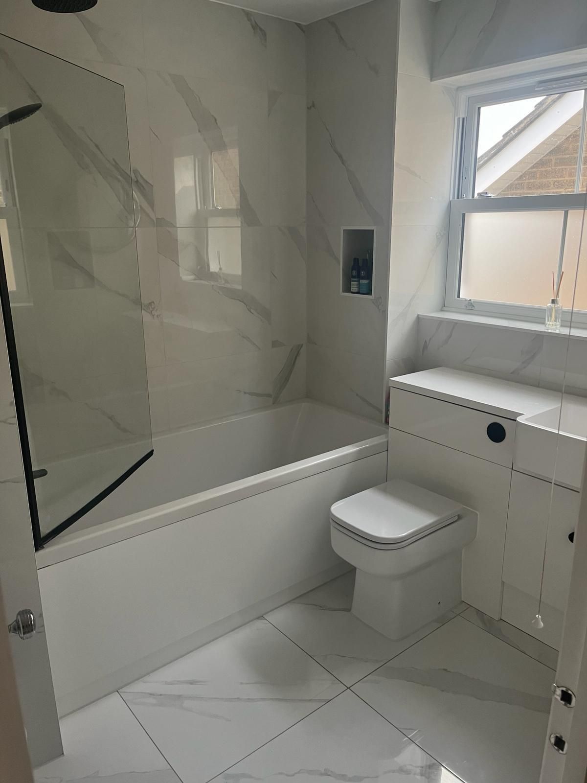 a bathroom with a bathtub , toilet , sink and window .