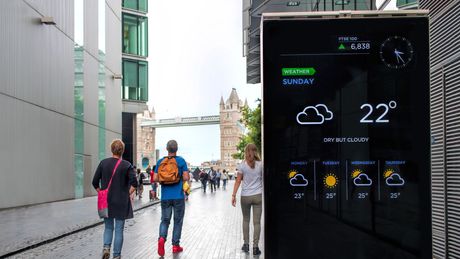 Mensen die door de straat lopen naast een bord waarop 22 graden staat