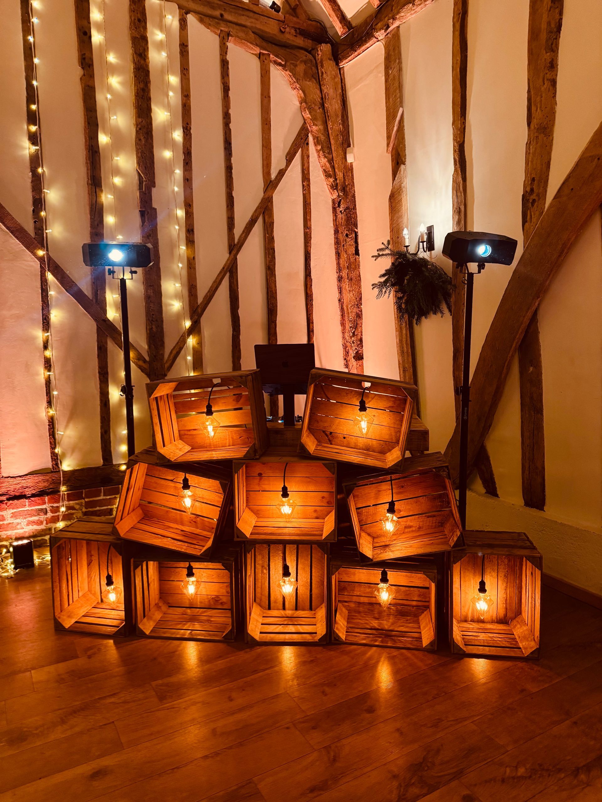Stacked wooden crates illuminated by internal Edison bulbs, arranged as a decorative display in a rustic room.