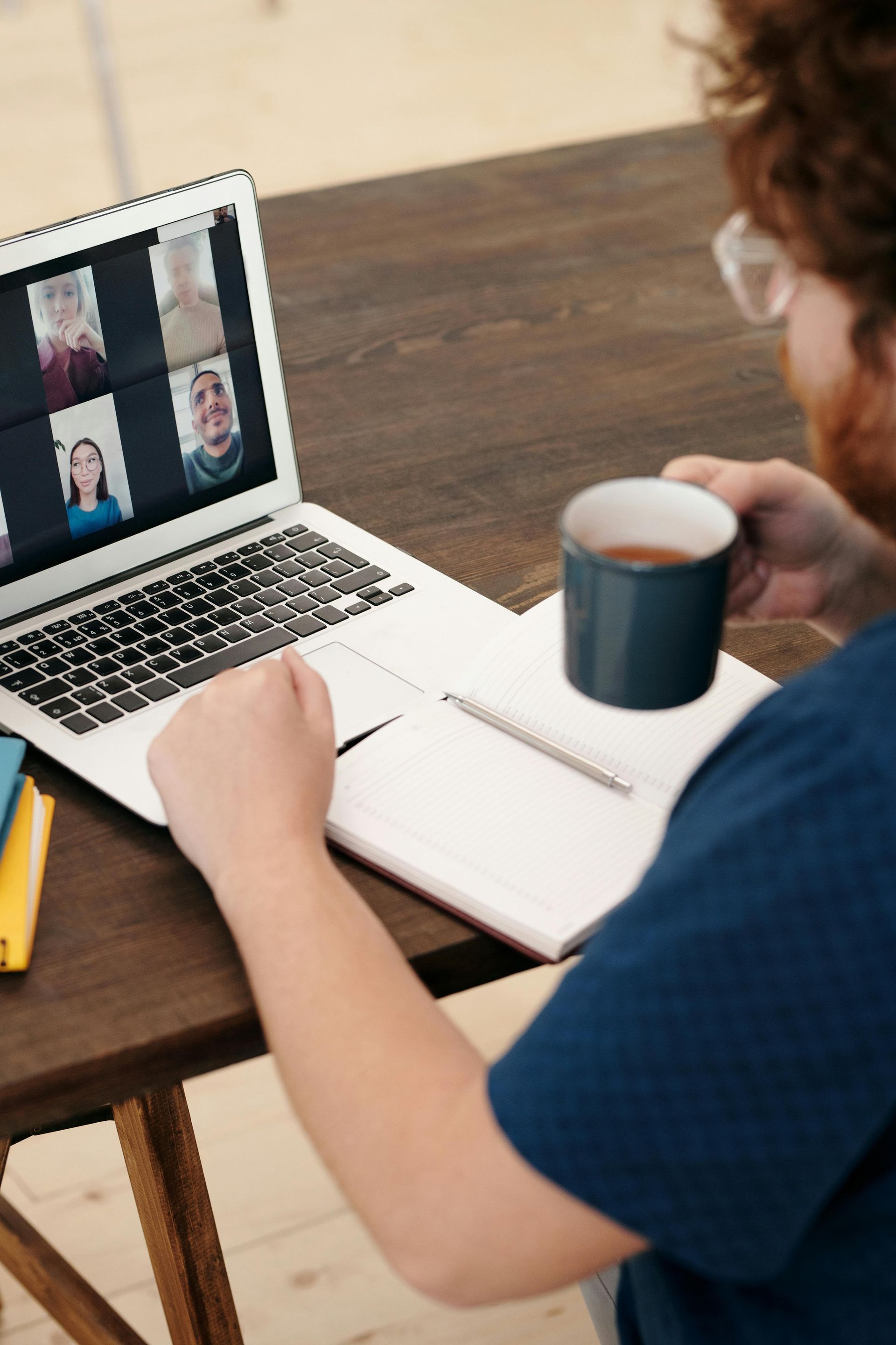 A man is sitting at a table with a laptop and a cup of coffee.