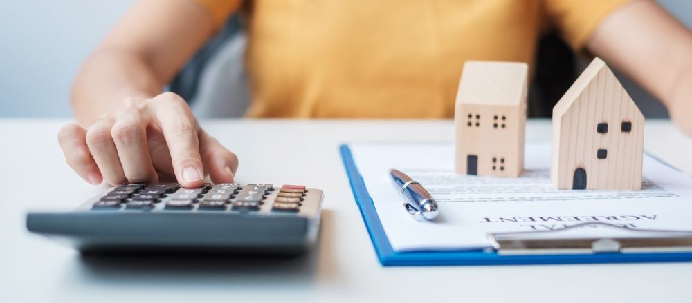 A person is using a calculator to calculate the cost of a house.