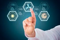 Hand touching a digital screen displaying icons of energy sources, including a wind turbine and the sun.