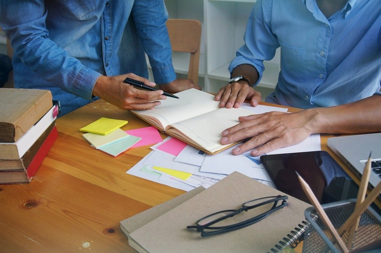 Two people are sitting at a table looking at a notebook.