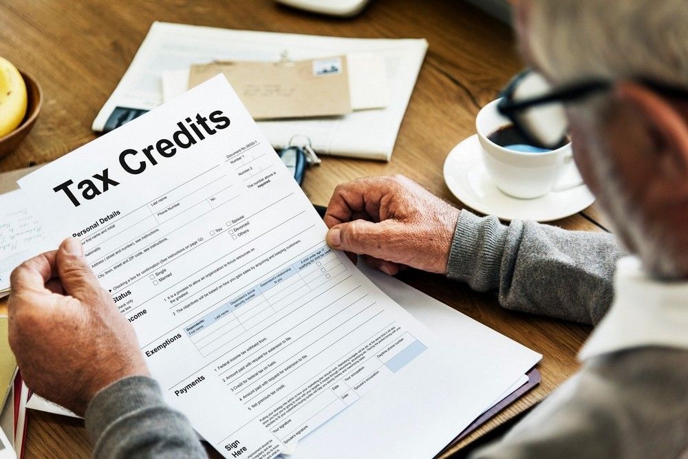 A man is sitting at a table looking at a tax credit form.