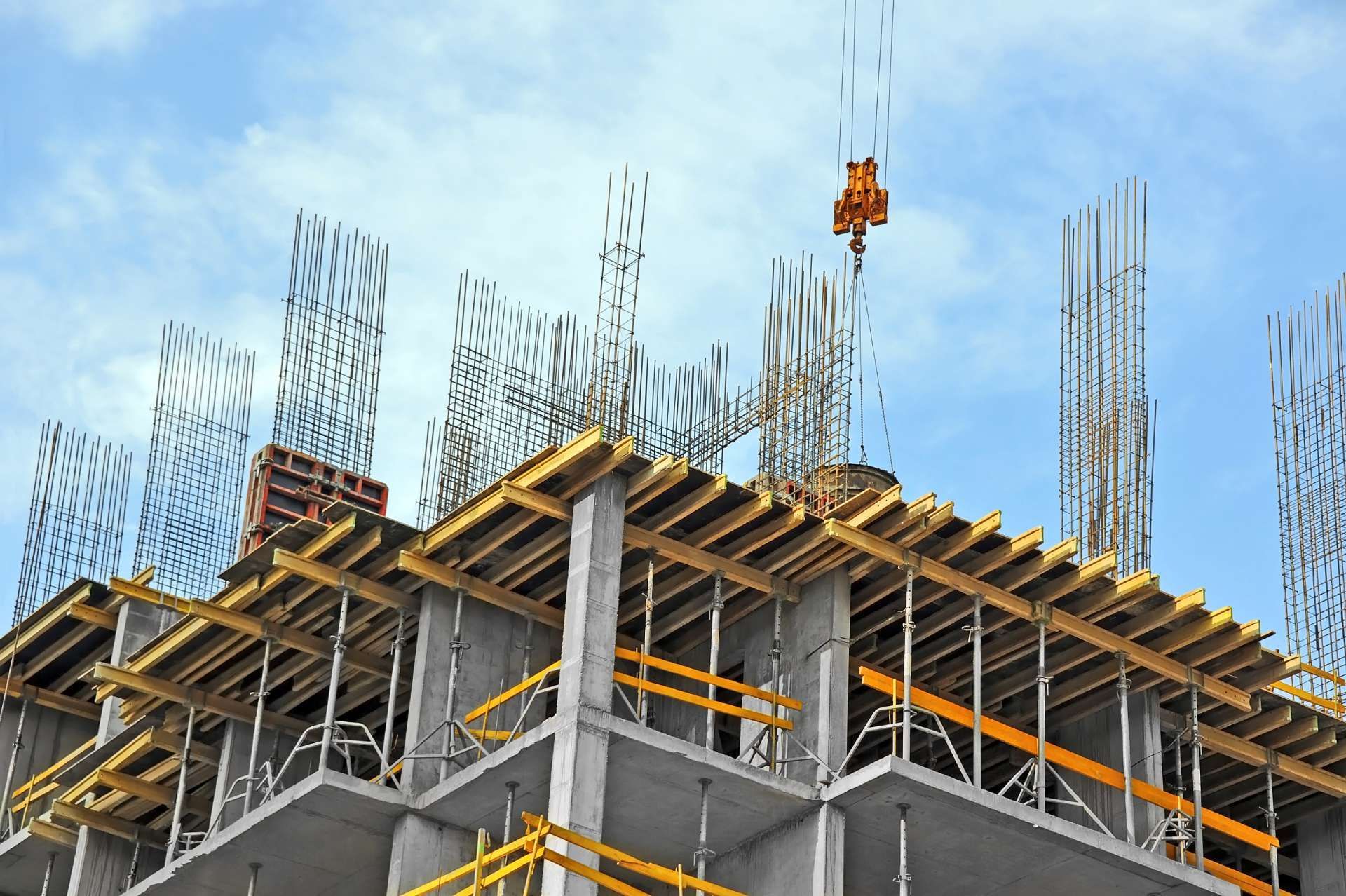 Construction of a multi-story building, showing concrete structure, wooden frameworks, and a crane.