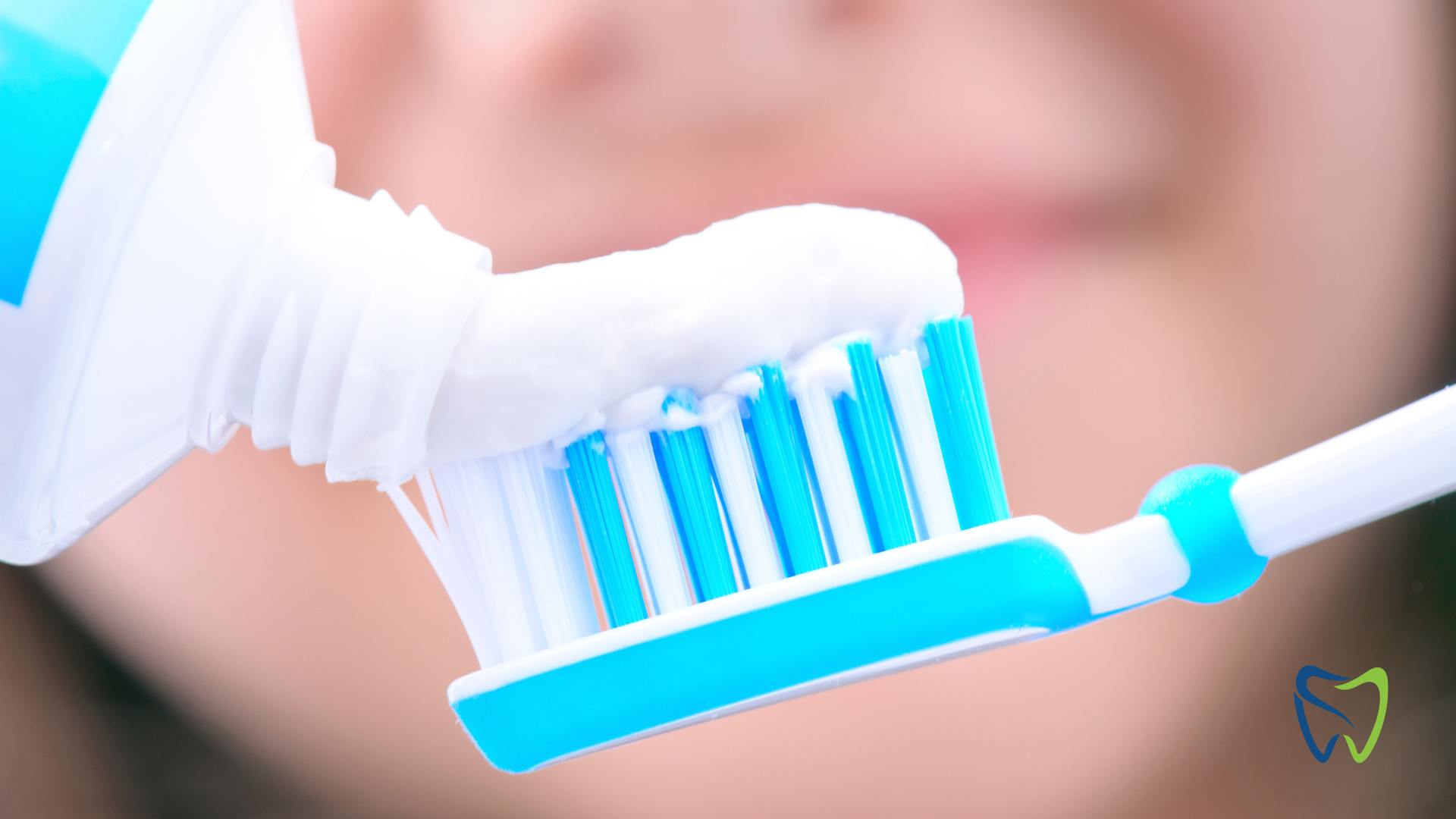 Toothpaste being squeezed onto a blue and white toothbrush.