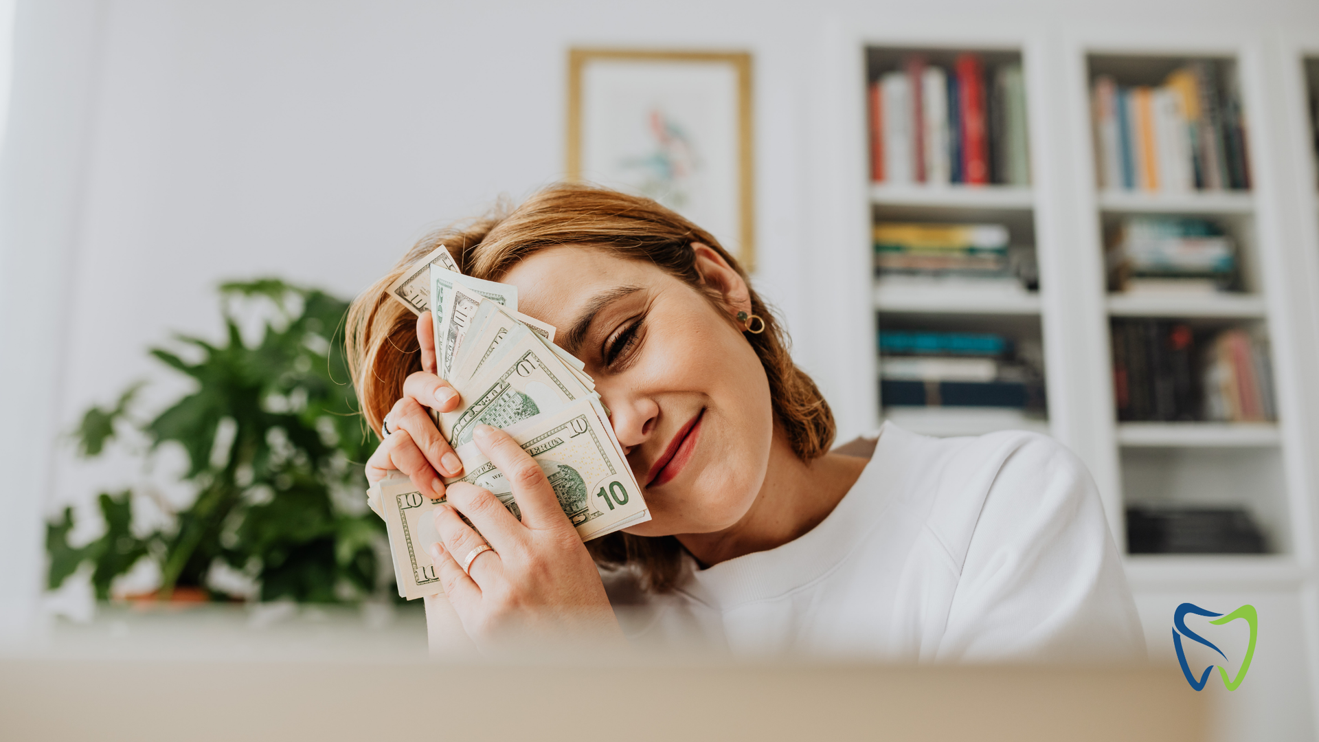 A woman is holding a pile of money in front of her face.
