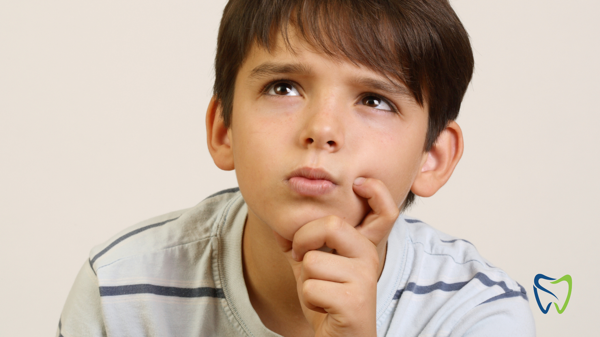 A young boy is thinking with his hand on his chin.